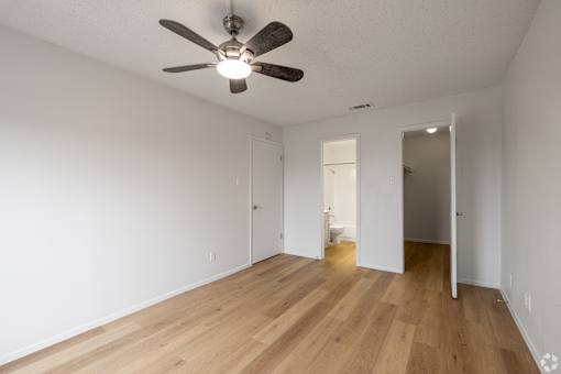 A room with a ceiling fan and wooden floors.