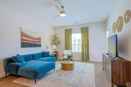 A living room with a blue couch and a television at The Virginia Apartments , Seguin, 78155