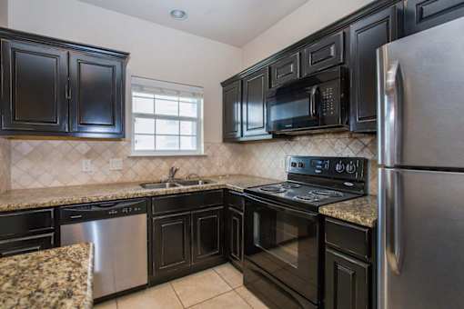 A kitchen with black cabinets and stainless steel appliances at Logan Ridge Apartments, San Marcos, 78666