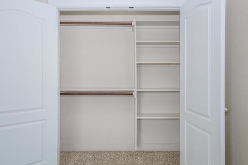 A white closet with shelves and a carpeted floor at Logan Ridge Apartments, San Marcos, TX, 78666