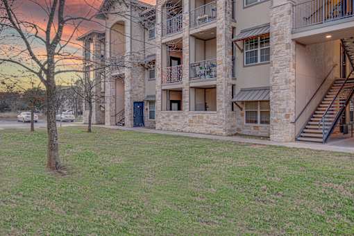 A large apartment complex with a grassy area in front at Logan Ridge Apartments, Texas
