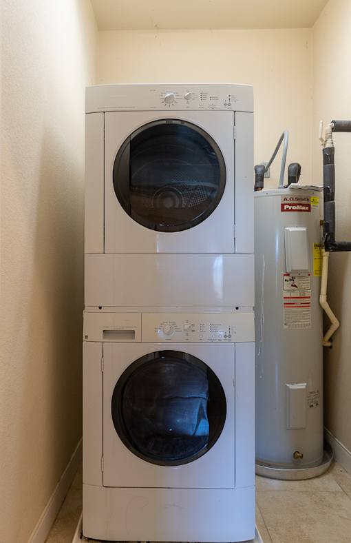 A white dryer and washer are stacked on top of each other at Logan Ridge Apartments, San Marcos