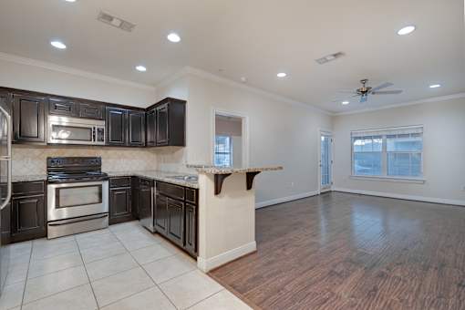 A kitchen with dark wood cabinets and stainless steel appliances at Logan Ridge Apartments, San Marcos, Texas