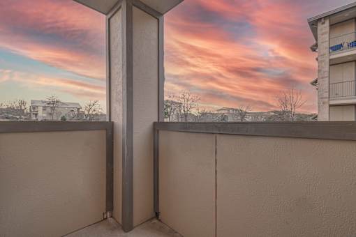 A balcony with a view of a sunset or sunrise at Logan Ridge Apartments, San Marcos, Texas