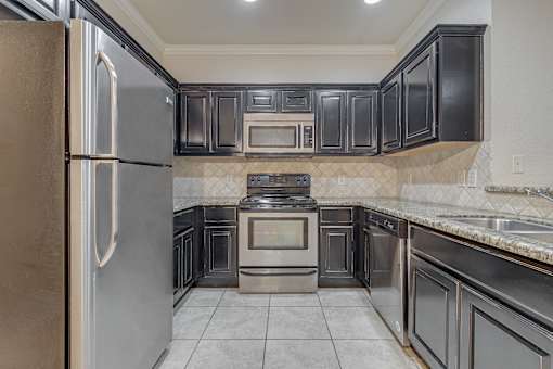 A kitchen with black cabinets and stainless steel appliances at Logan Ridge Apartments, Texas, 78666
