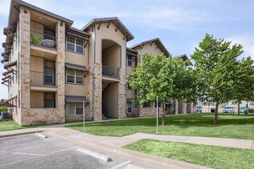 A large apartment complex with a parking lot in front at Logan Ridge Apartments, Texas