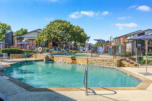 A large outdoor swimming pool surrounded by a fence and trees at Water Ridge Apartments , Irving, 75061