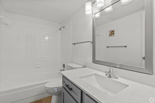 A white bathroom with a toilet, sink, and mirror.