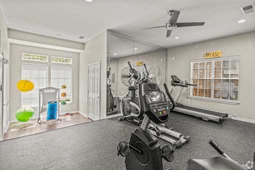 A gym with a variety of equipment including a treadmill, stationary bike, and a rowing machine.