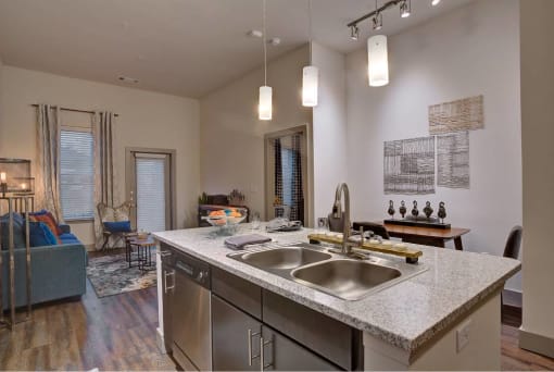 a kitchen with a sink and a view of a living room at The Grand at Stonecreek, San Marcos, TX