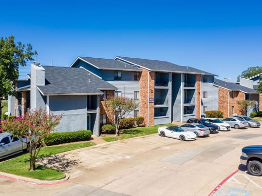 an apartment building with many cars parked in front of it at Water Ridge Apartments, Irving, TX 75061