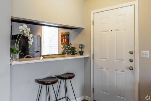 a bar with two stools in a kitchen with a white door at Water Ridge Apartments, Texas