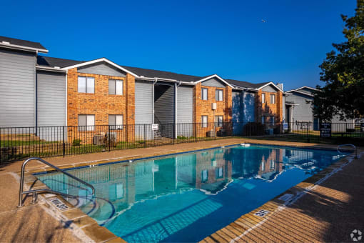 a swimming pool in front of apartments with a pool at Water Ridge Apartments, Texas