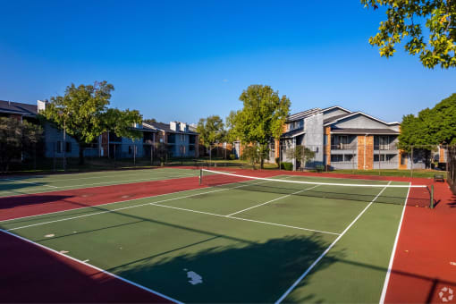 a tennis court with apartments in the background at Water Ridge Apartments, Irving, TX 75061