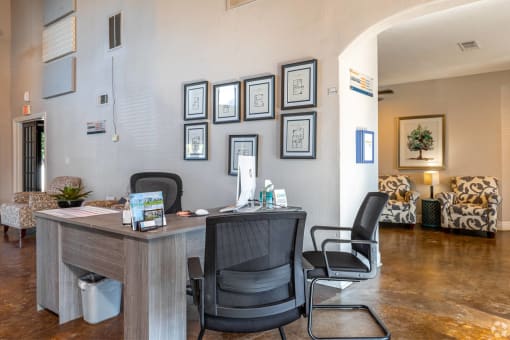 an office with a desk and chairs in front of a wall with photos on it at Water Ridge Apartments, Irving, TX
