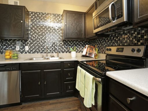 a kitchen with black cabinets and a stove and a sink at Water Ridge Apartments, Irving
