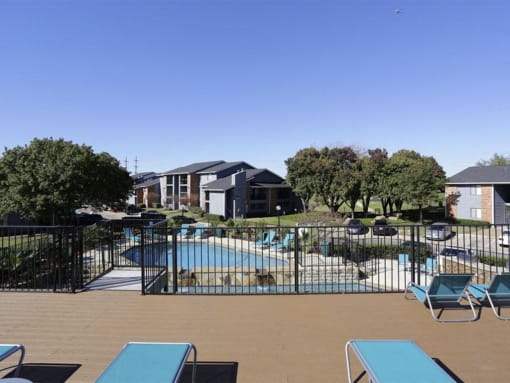 a pool with lounge chairs and a fence at Water Ridge Apartments, Irving, 75061