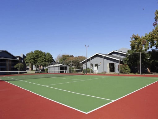a tennis court with houses and trees in the background at Water Ridge Apartments, Irving, TX