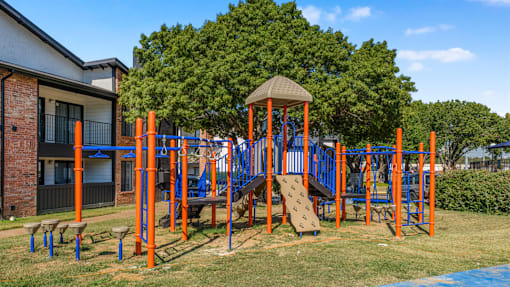 A playground with a slide, swings, and a climbing frame at Water Ridge Apartments , Irving, Texas