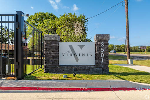 A sign that says Virginia is on a stone pillar at The Virginia Apartments , Seguin, TX