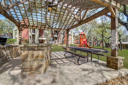 A picnic table is under a wooden pergola.