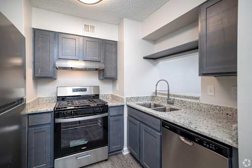 A kitchen with a stove, sink and refrigerator.