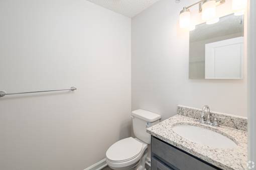 A bathroom with a toilet, sink and mirror.