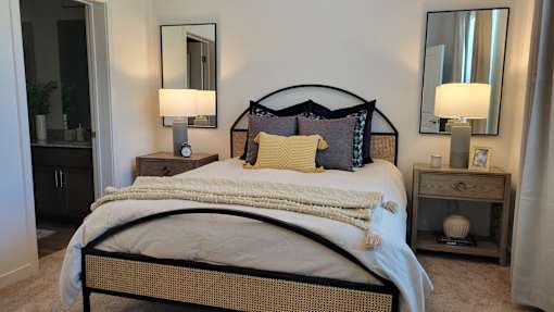 A bed with a white comforter and a pillow with a blue design on it.