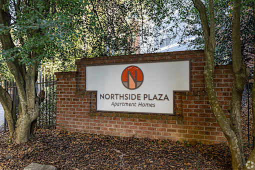 A sign for Northside Plaza Apartment Homes is displayed on a brick wall.