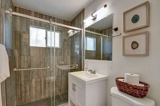 A bathroom with a white sink and a glass shower stall.
