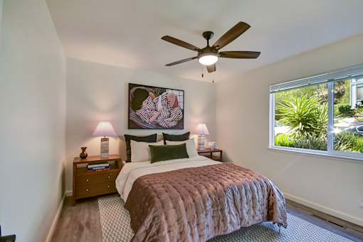A bedroom with a bed, nightstands, and a ceiling fan.