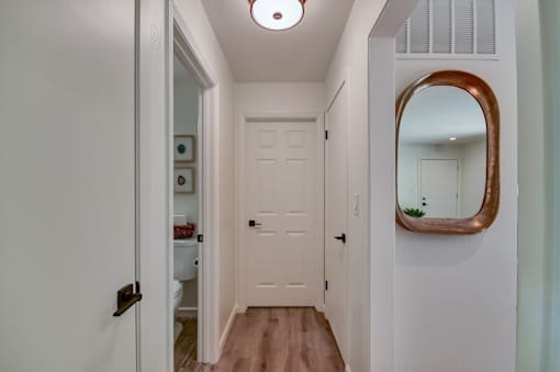 A hallway with a white door and a mirror on the wall.