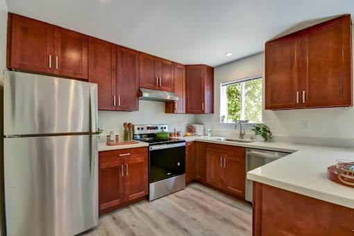 A kitchen with wooden cabinets and a stainless steel refrigerator.