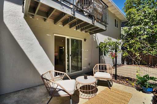 A patio with a chair and table outside a house.