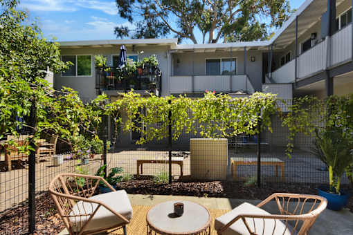 A patio with chairs and a table surrounded by a fence.