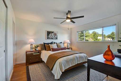 A bedroom with a bed, nightstand, and a ceiling fan.