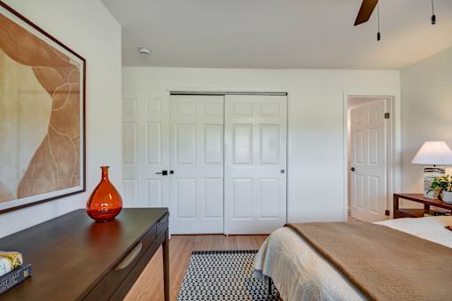 A bedroom with a bed, a dresser, and a painting on the wall.