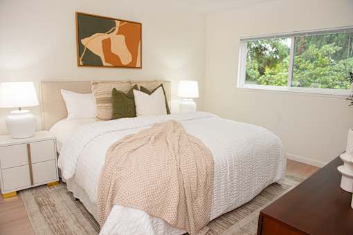 A bedroom with a large bed and a painting above it.