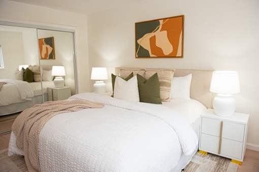 A bedroom with a large bed and a painting on the wall.