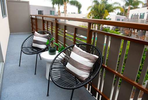 Two chairs and a table on a balcony.