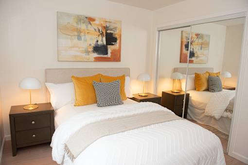 A bedroom with a large bed, a nightstand, and a painting on the wall.