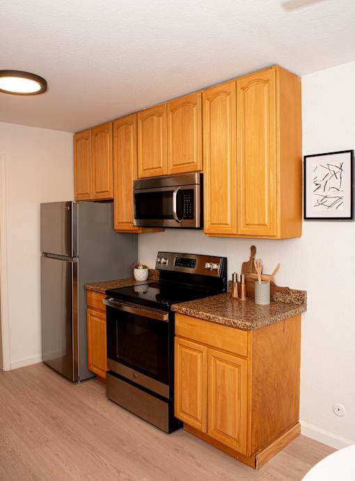 A kitchen with wooden cabinets and a black counter top.