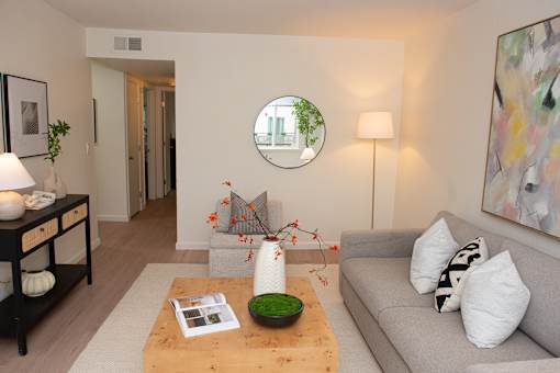A living room with a grey couch, a coffee table, and a painting on the wall.