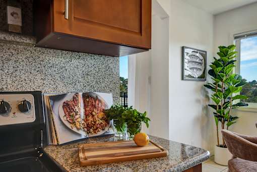 A kitchen with a black stove top oven and a cutting board with an orange on it.