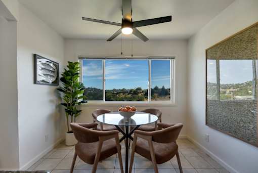A dining room with a table and chairs and a ceiling fan.