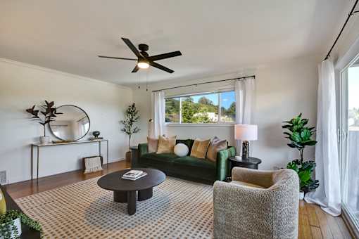 A living room with a green couch, a coffee table, and a ceiling fan.