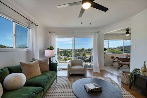 A living room with a green couch and a ceiling fan.