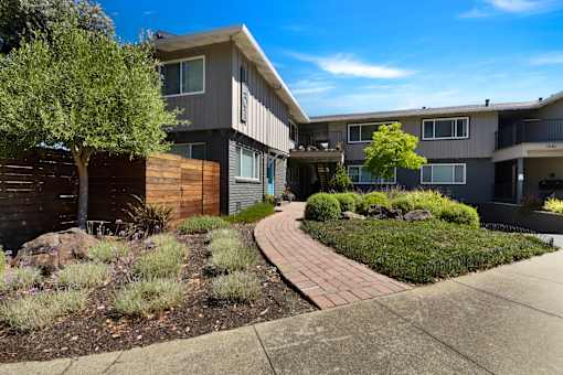 A modern apartment complex with a landscaped garden in front.