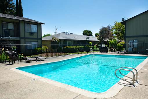 A swimming pool surrounded by a fence and chairs.