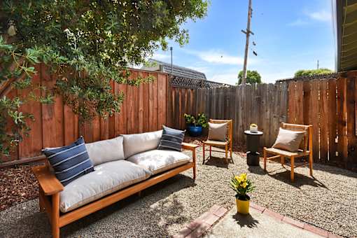 A backyard with a wooden bench and chairs.